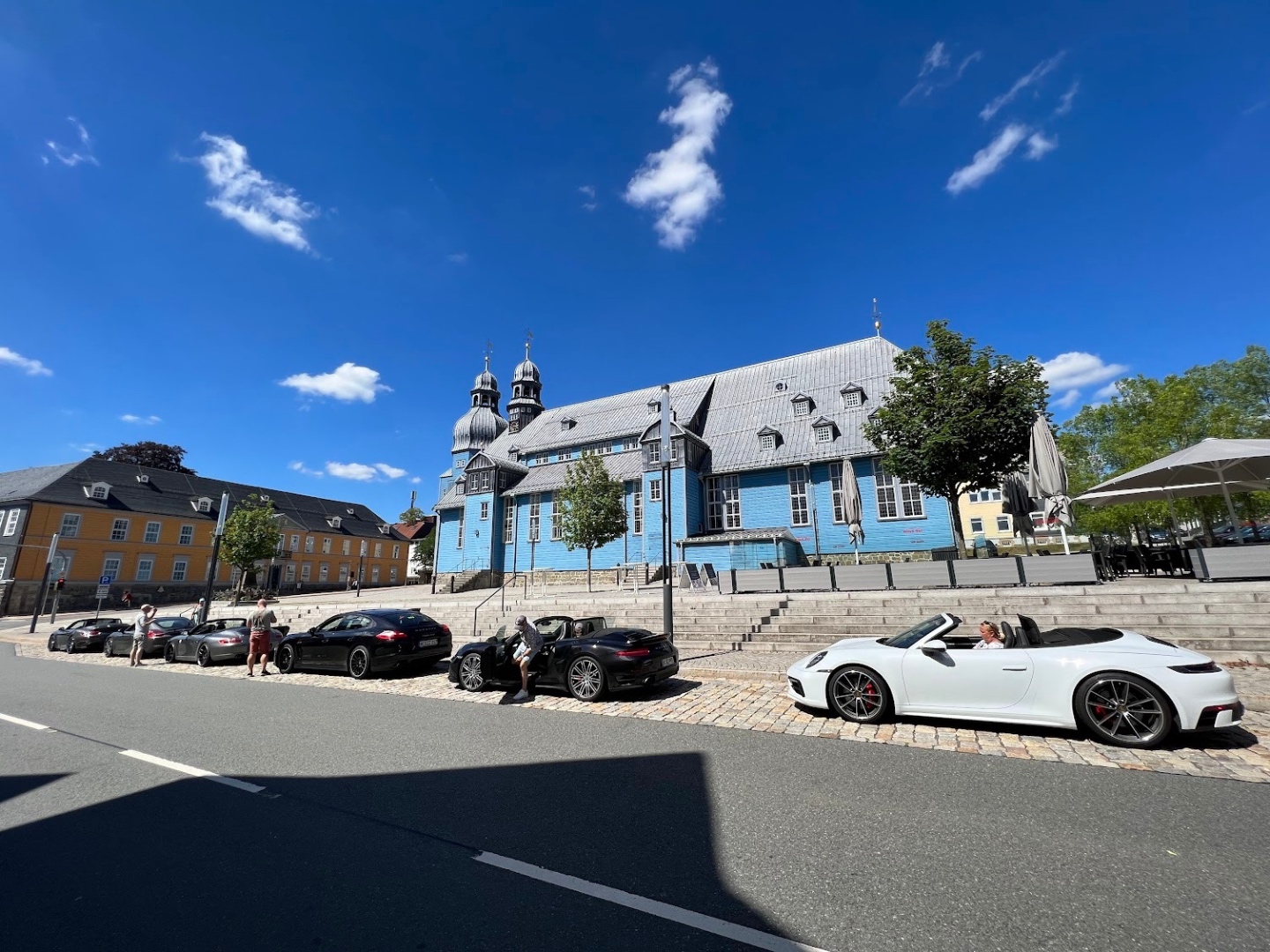 Porsches parked on cobblestones in front of a historic German town square