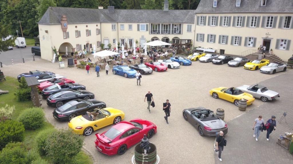 Over 20 Porsches gathered in a castle courtyard