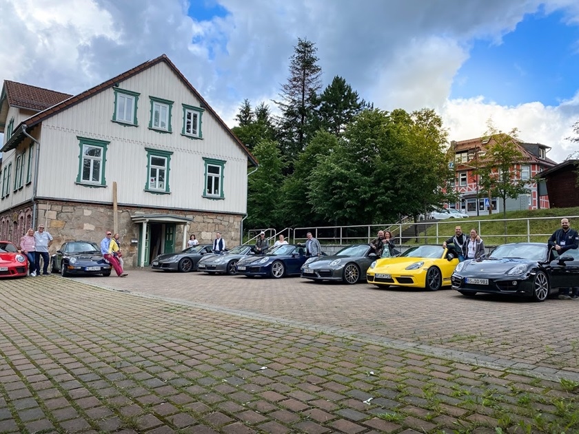 Group of Porsches and people at a traditional German house