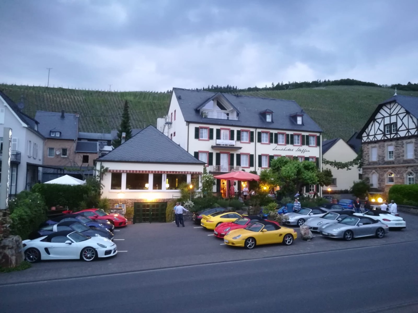 Porsches at a charming German hotel at dusk with vineyard hills